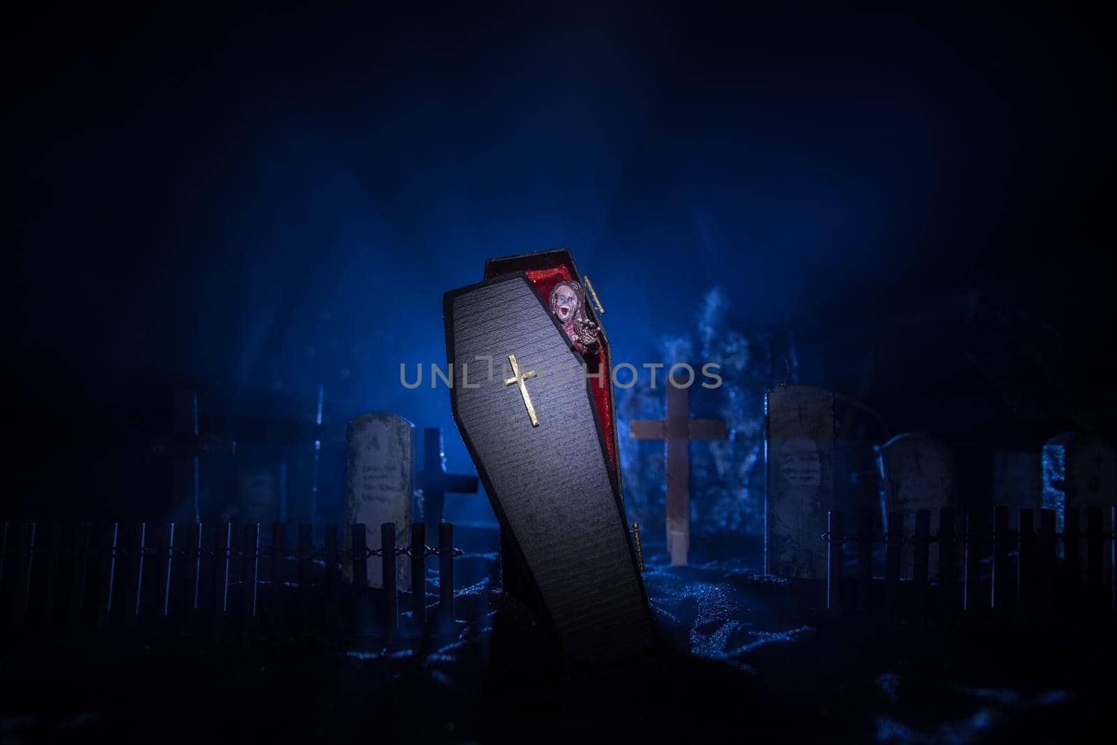 Creative artwork. Miniature wooden coffin with zombie inside. Scary view of zombies at cemetery. Horror Halloween concept. Selective focus