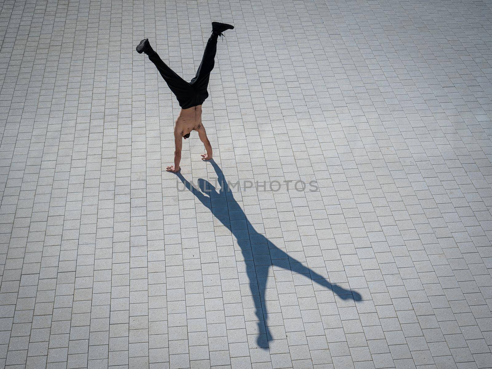 Shirtless man walks on his hands outdoors. View from above. by mrwed54