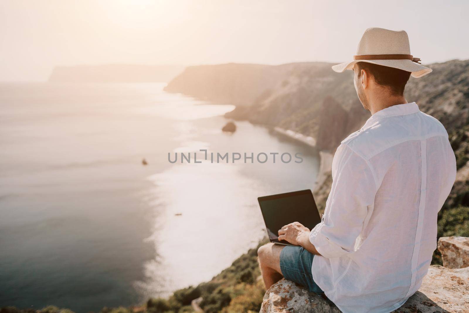 freelancer businessman working remotely on laptop at the beach near the sea