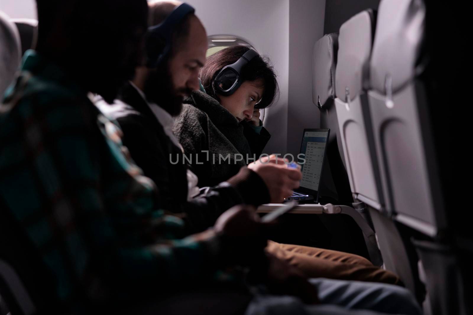 Multiethnic group of passengers flying abroad by airplane jet, using modern devices during international plane transportation. Travelling in economy class with airways flight trip.