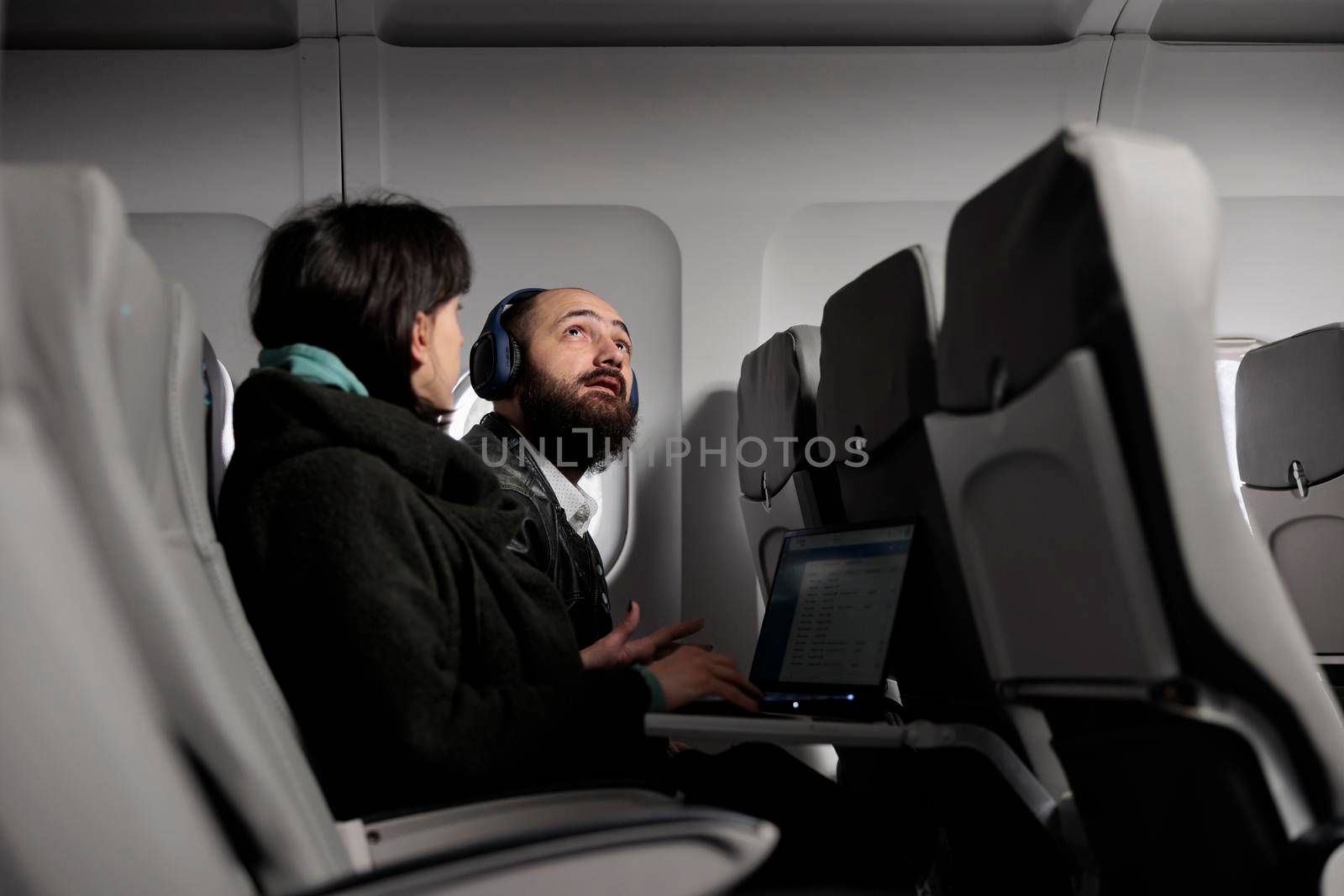 Man tourist preparing to takeoff on airplane flight, getting ready to fly with international airline. Travelling in economy class with woman to arrive at holiday destination, air transportation.