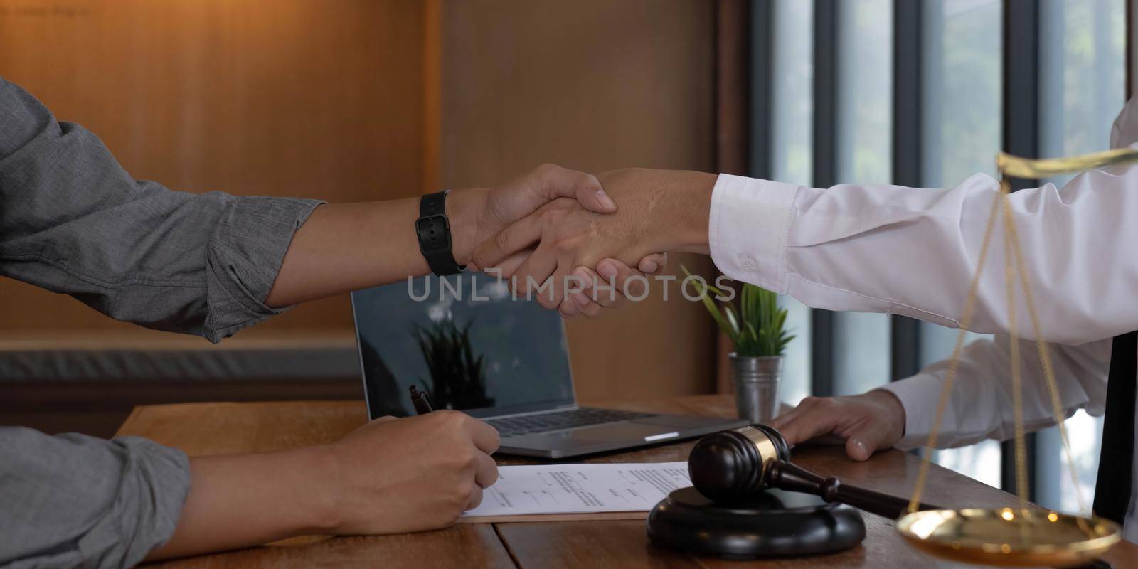 Businessman shaking hands to seal a deal with his partner lawyers or attorneys discussing a contract agreement by wichayada