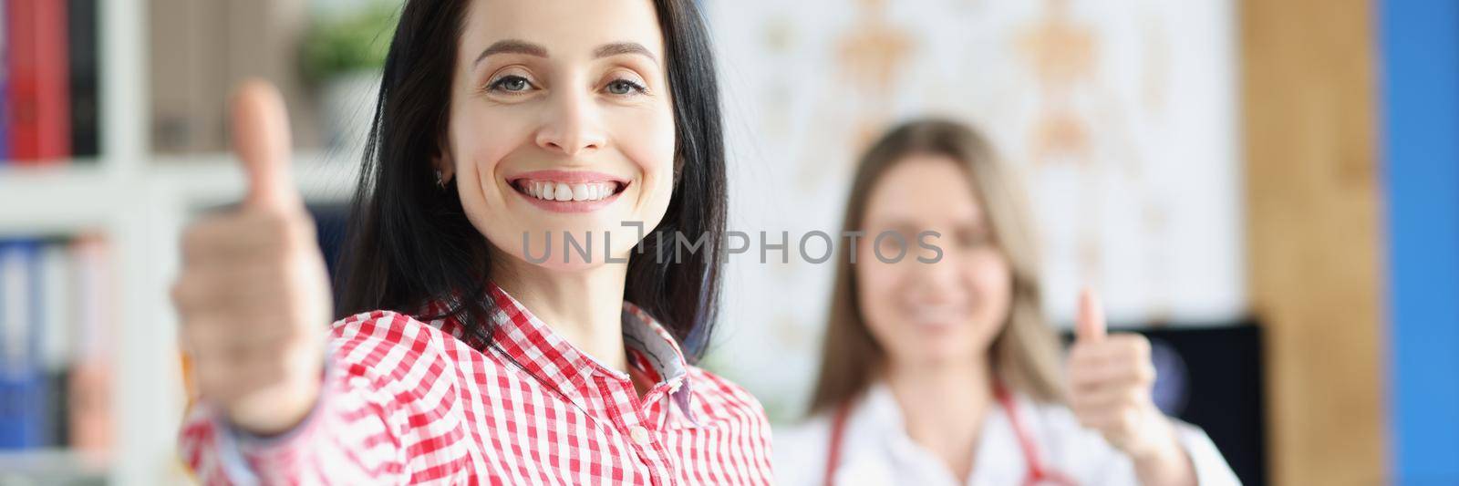 Portrait of happy woman patient show thumbs up gesture, woman healthy after treatment. Doctor support patient and celebrate with her. Win disease concept