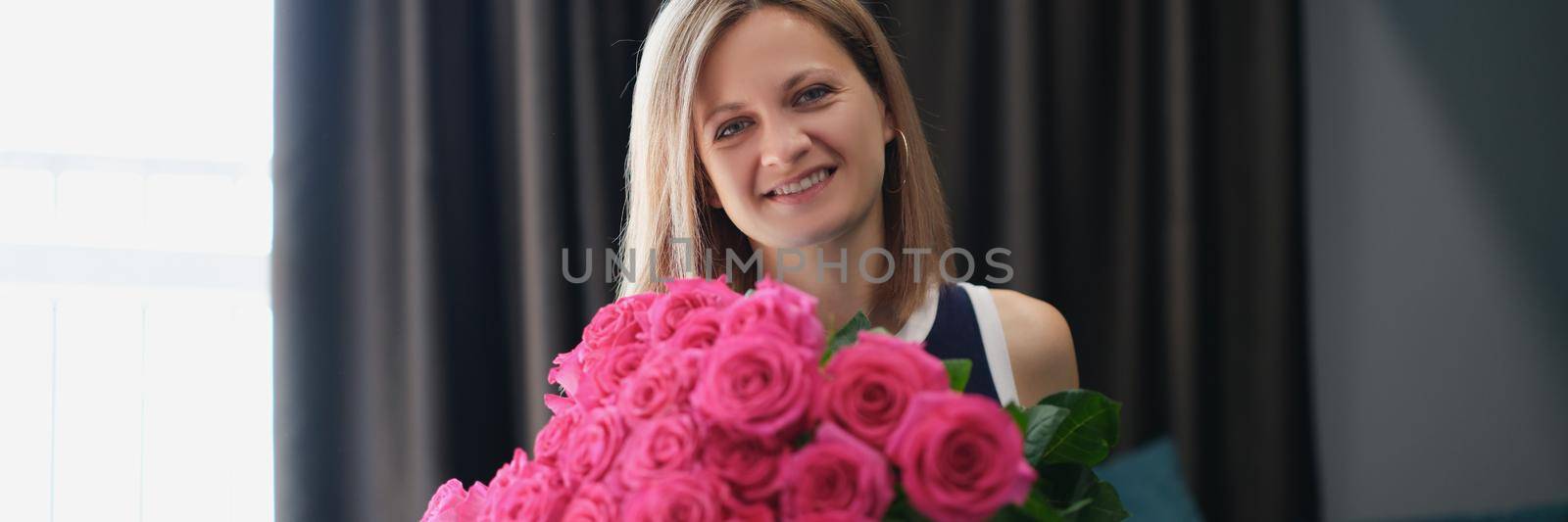 Portrait of beautiful young woman get bouquet of flowers on birthday or anniversary. Pink roses present from husband or friend. Attention, beauty concept