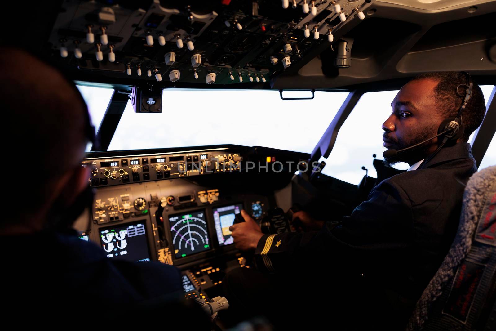 African american pilot flying aircraft jet doing teamwork with captain, using dashboard command and navigation. Team of airliners pushing control panel buttons and lever to takeoff and fly.