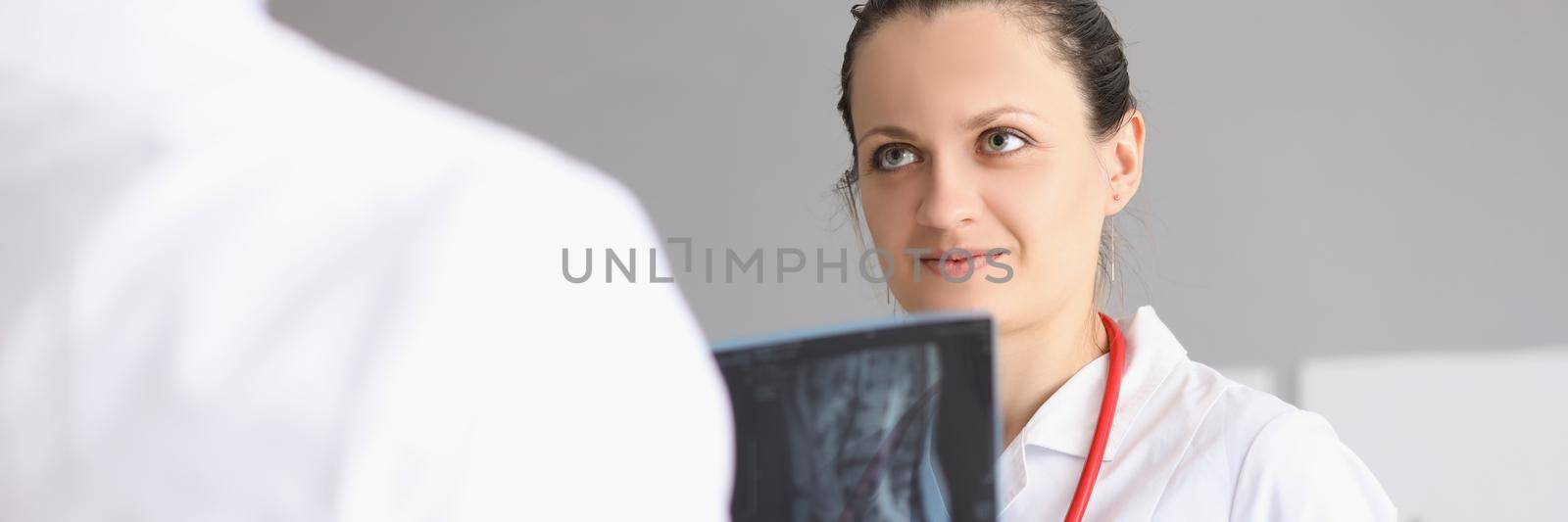 Portrait of female doctor discuss with colleague patient x ray result. Worker hold scan result of clients checkup. Medicine, treatment, diagnostic concept
