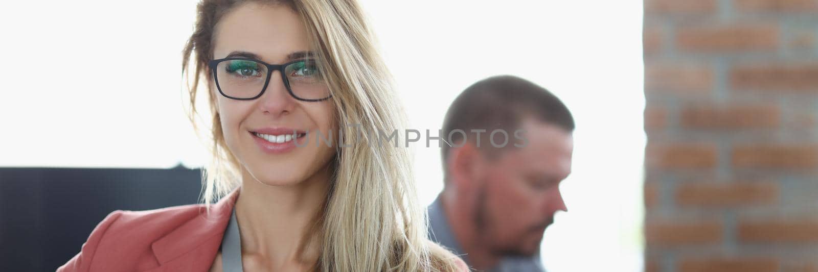 Portrait of stunning worker woman in presentable suit on working place, colleagues work together and share office space. Success, business, career concept