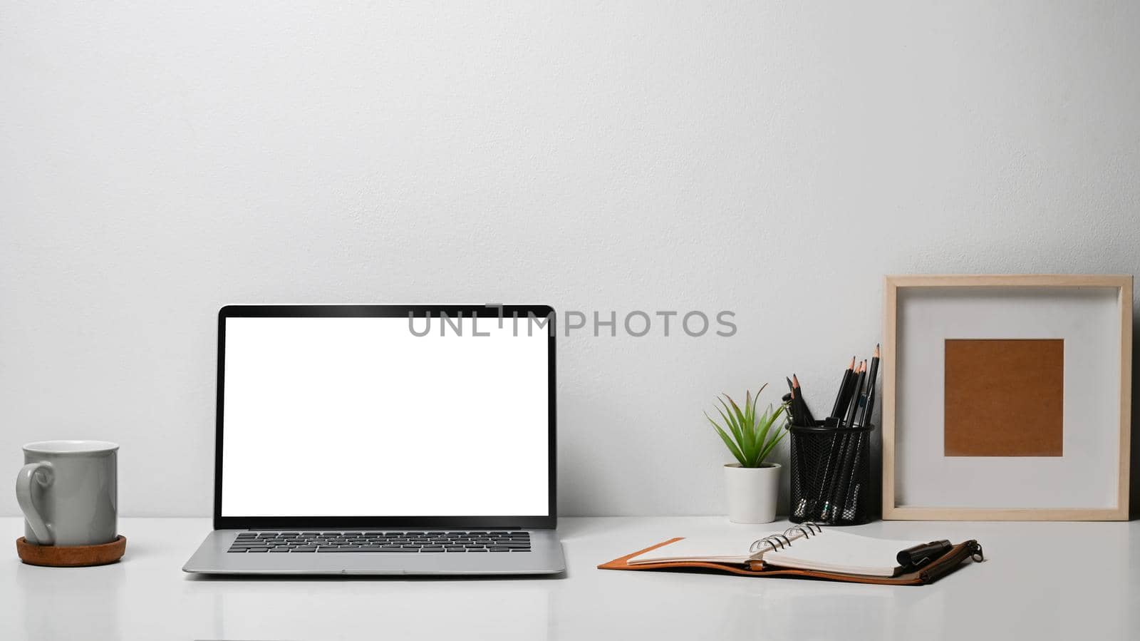 Mock up laptop computer, coffee cup, stationery and picture frame on white table by prathanchorruangsak