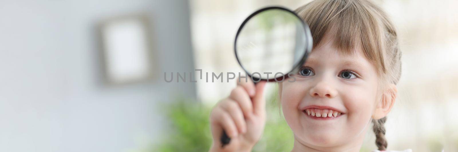 Pretty little child hold magnifying glass and explore world through it by kuprevich