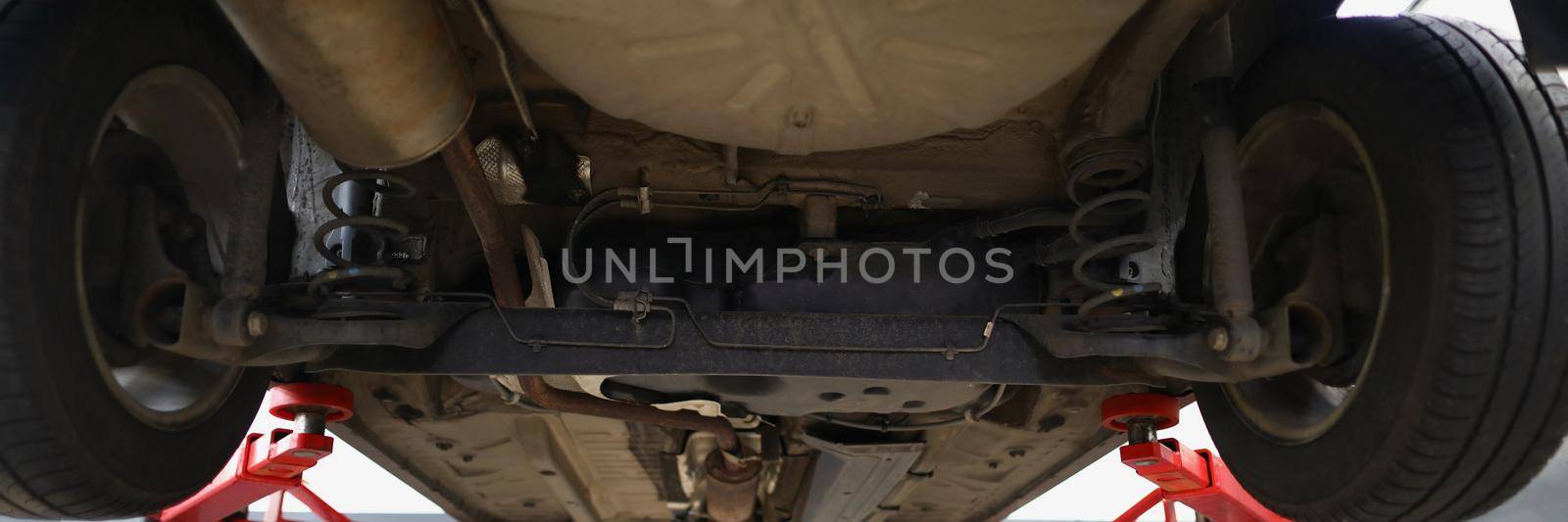 Car lifted in maintenance service to check condition, undercarriage of automobile by kuprevich