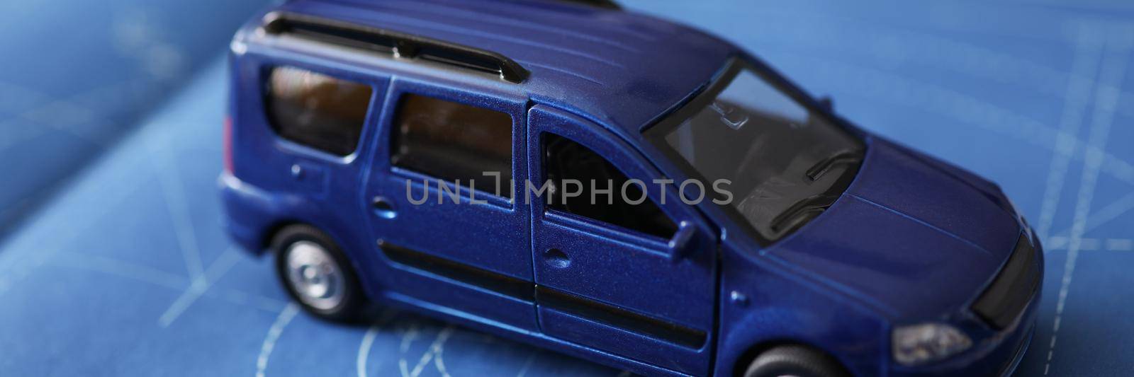Close-up of new car model development, miniature automobile model on blueprint paper. Think about car insurance policy. Protection, safety, project concept