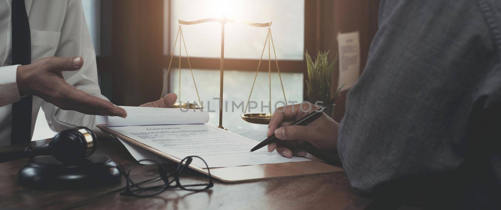 Businessman and lawyers discussing contract papers with brass scale on wooden desk in office. Law, legal services, advice, Justice concept..