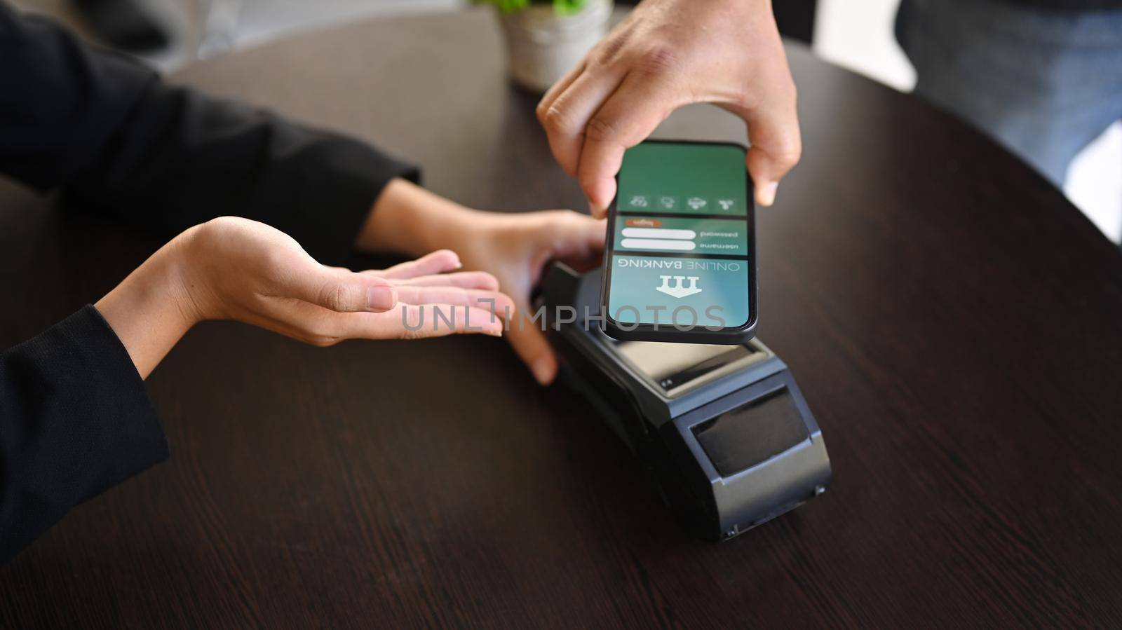 Customer using smartphone for payment to in coffee shop.