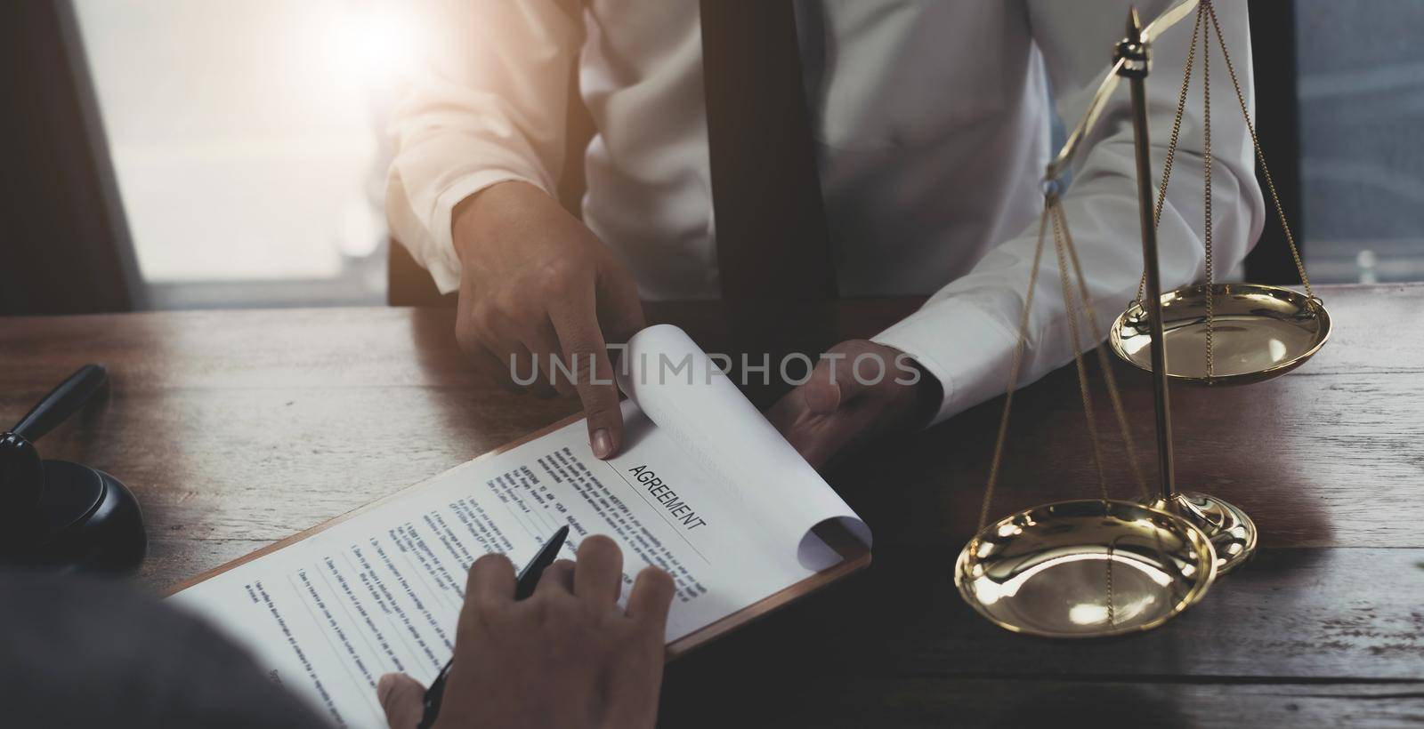 Business and lawyers discussing contract papers with brass scale on desk in office. Law, legal services, advice, justice and law concept picture with film grain effect.