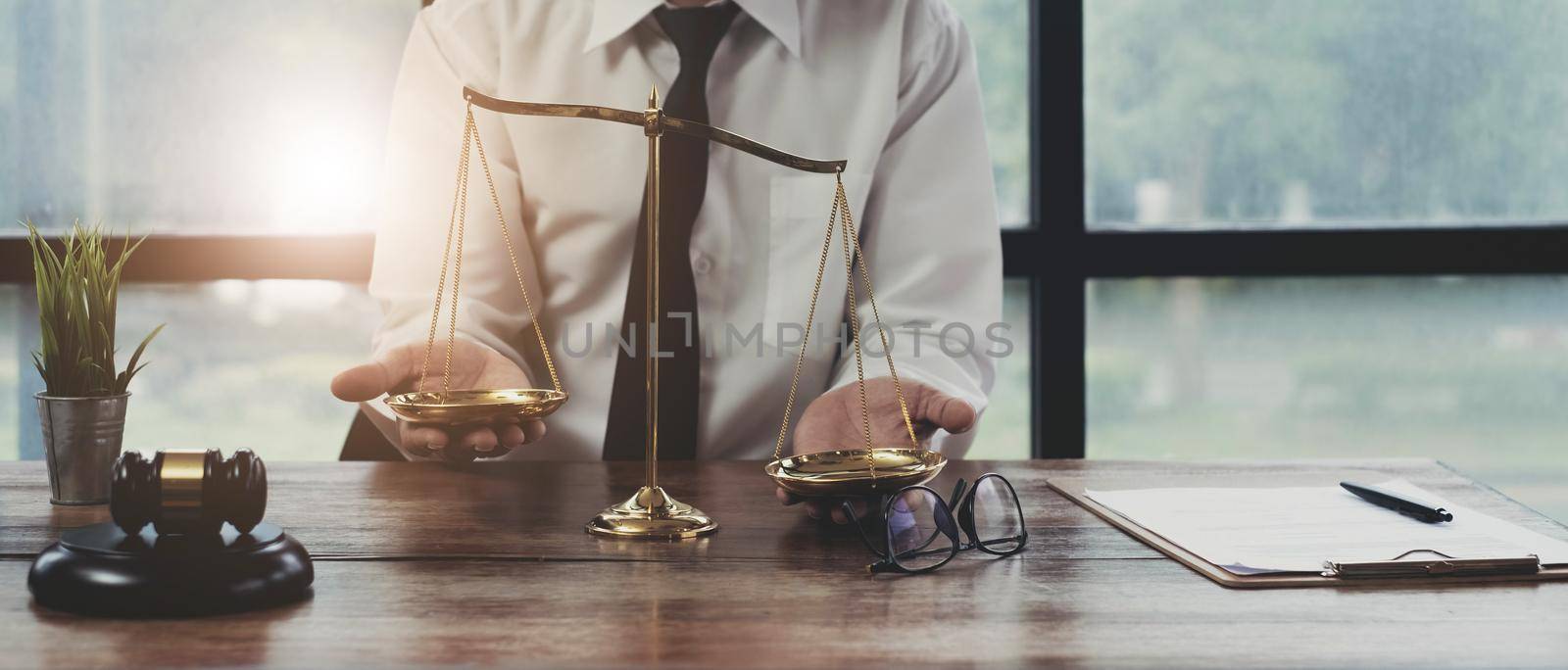 Male lawyer at table in office, focus on scales of justice.