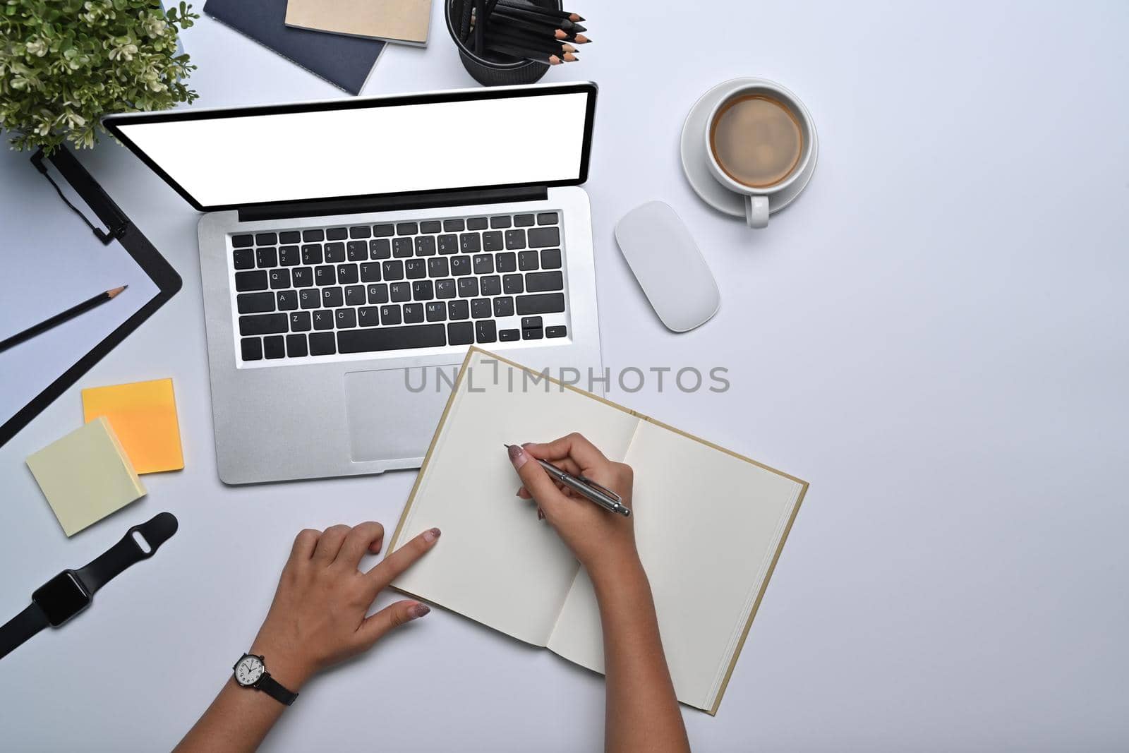 Businesswoman working with laptop and making notes on notebook. by prathanchorruangsak