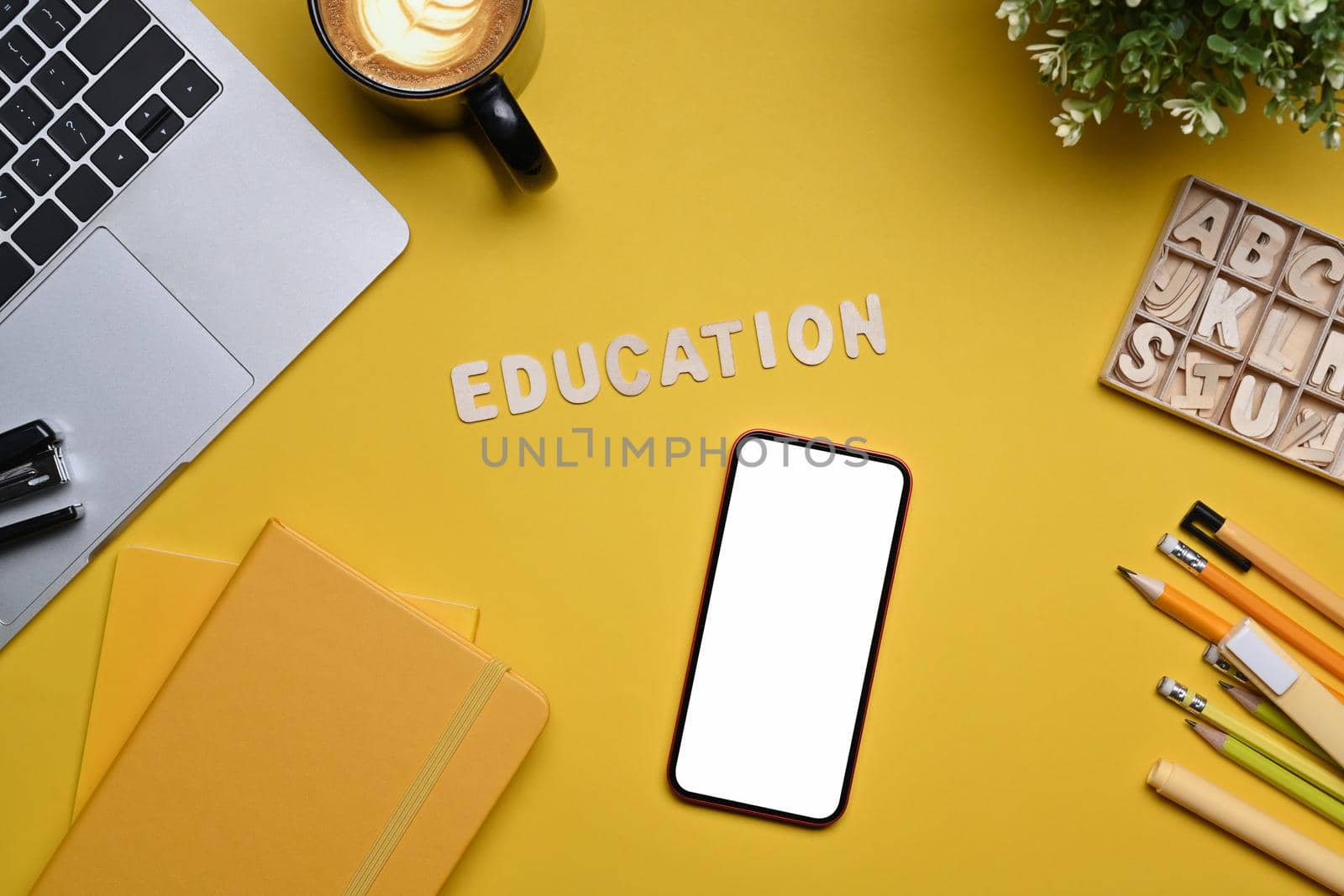 Top view smart phone, laptop computer and stationery on yellow background. Back to school concept.
