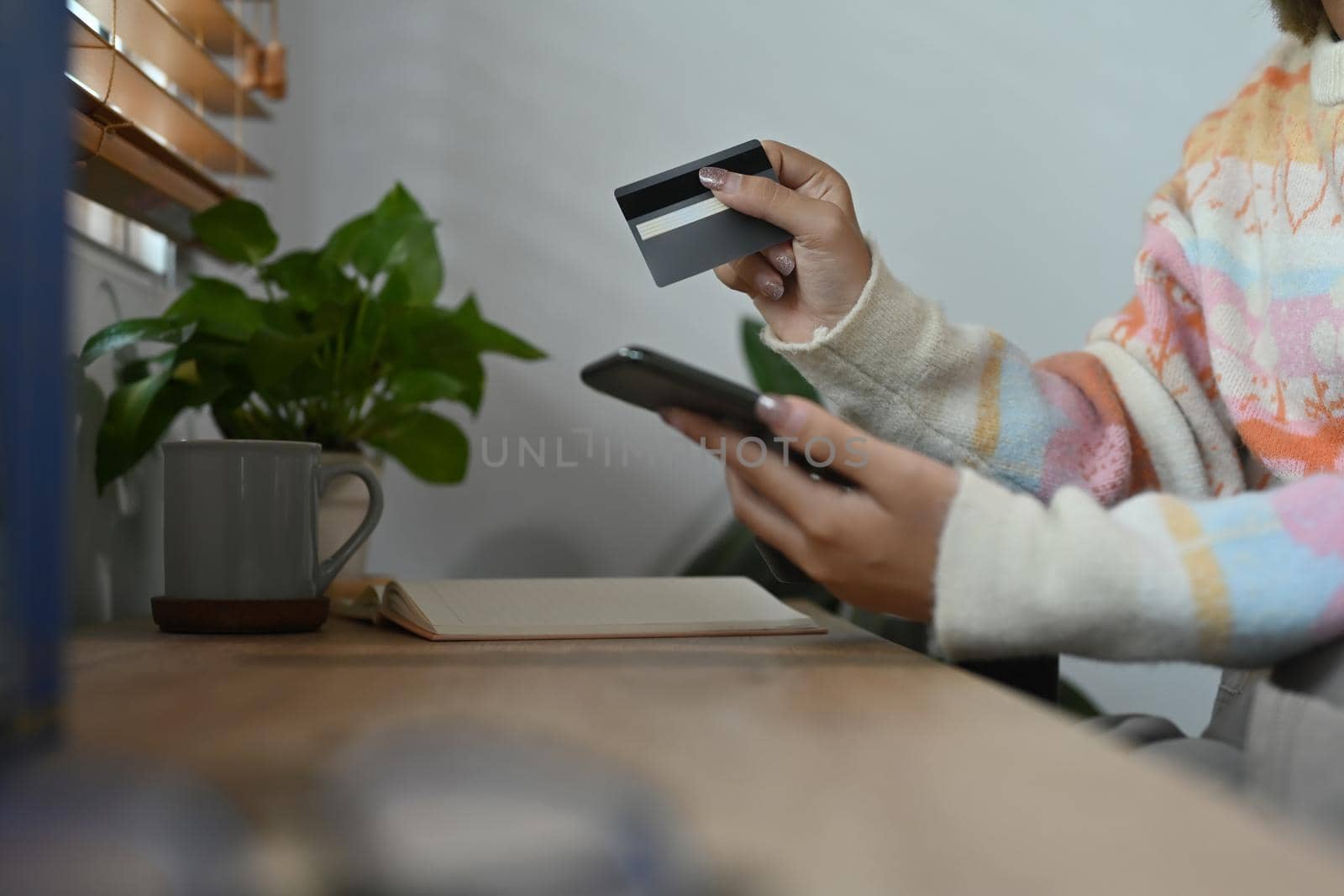 Cropped shot female holding credit card and making banking online with smart phone.