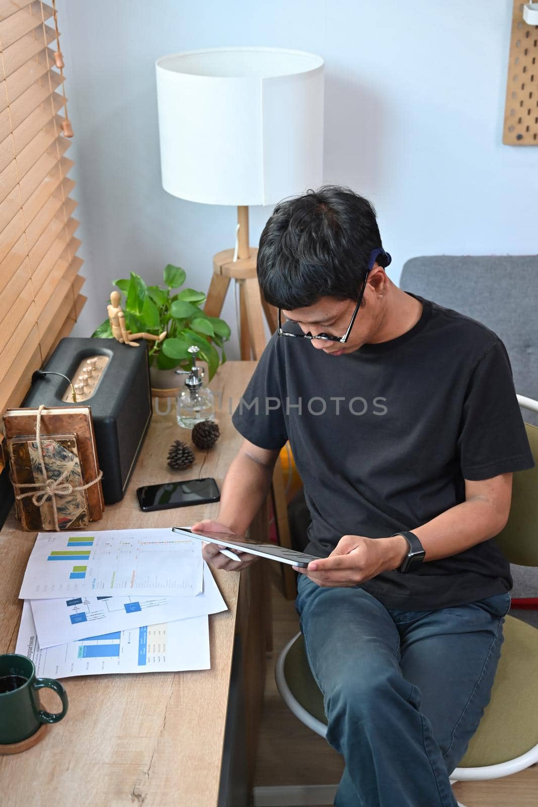 Young man analyzing graph stock market trading on digital tablet. by prathanchorruangsak