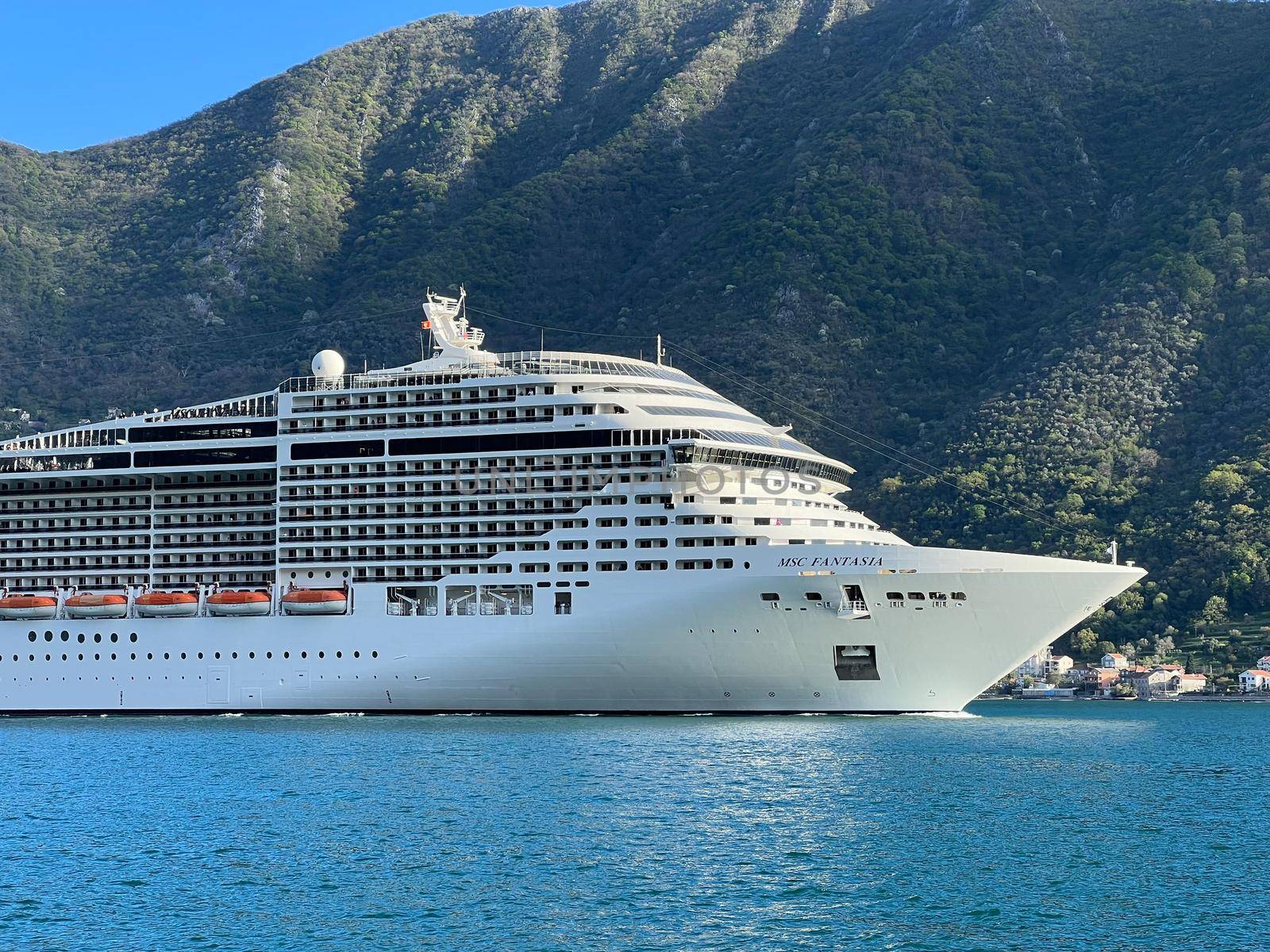 Huge cruise ship sails along the bay past the mountains. Montenegro. High quality photo