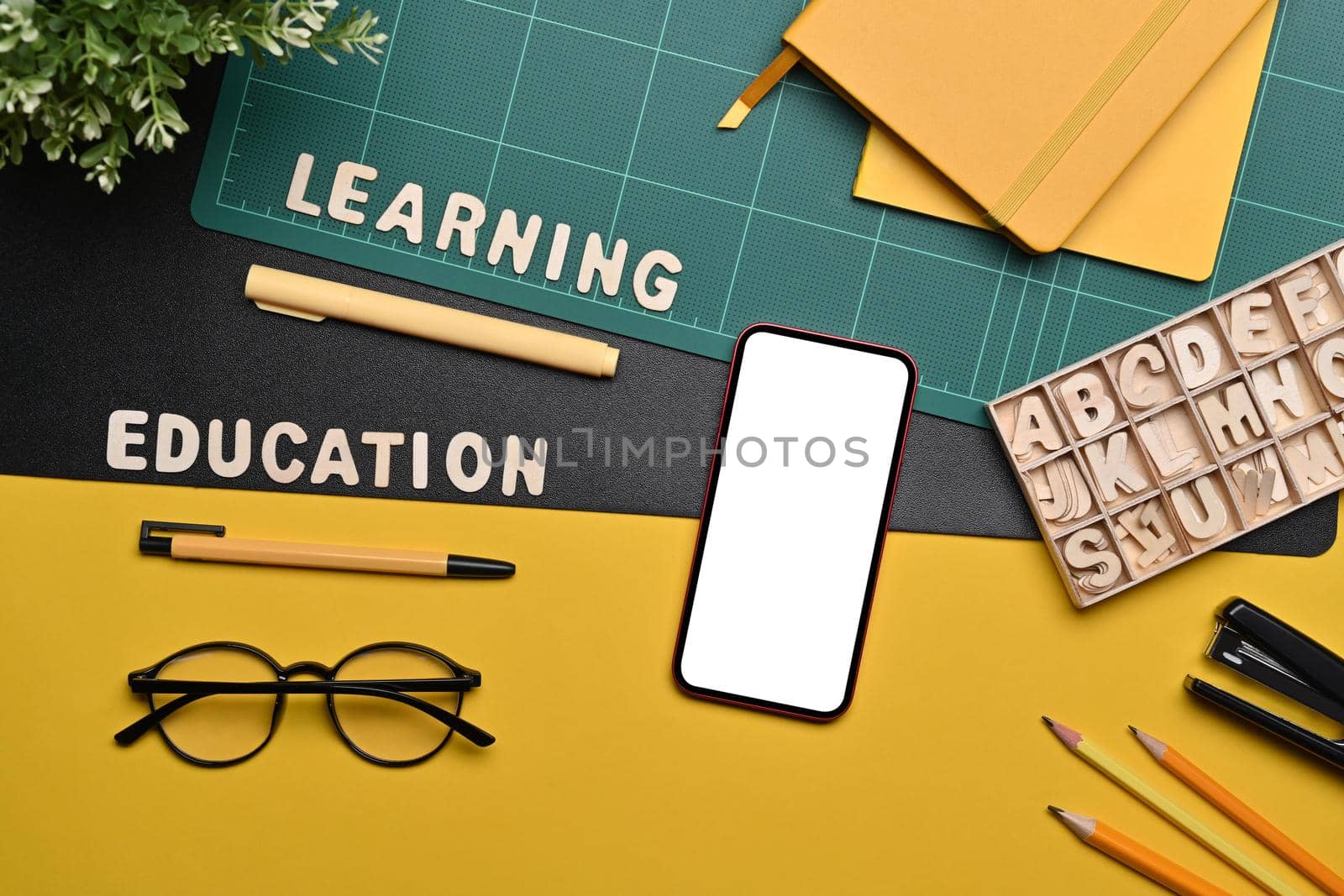 Mock up smart pone with white screen, glasses and stationery on colorful background.