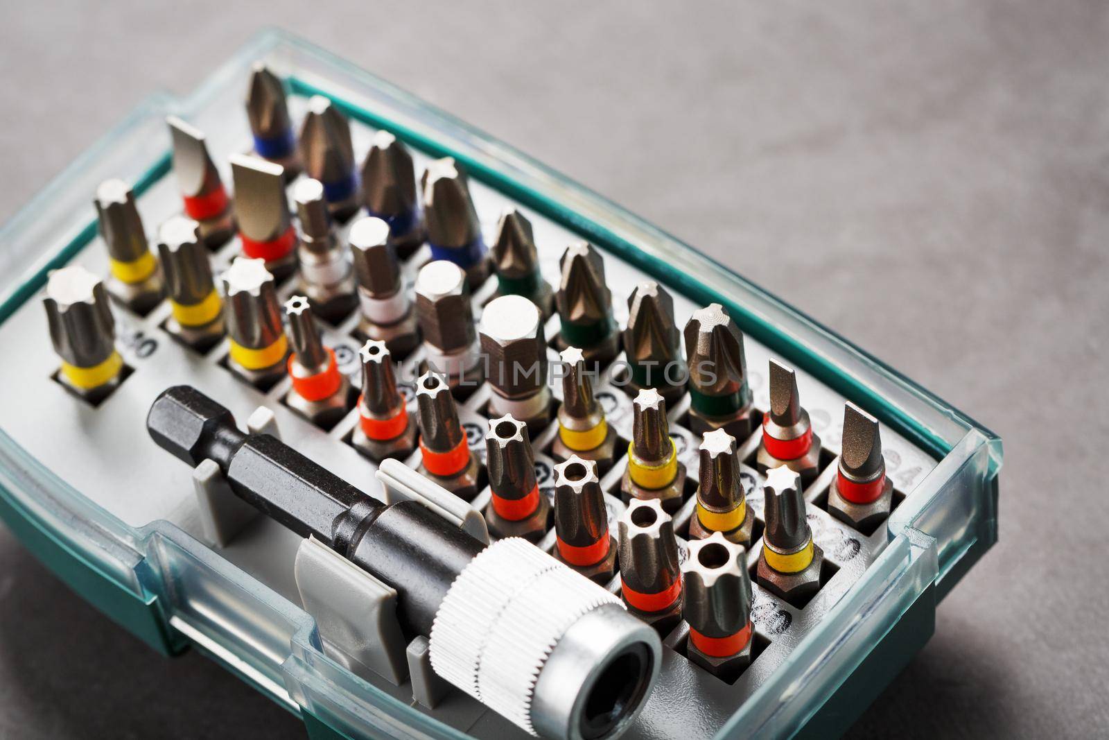 A set of metal power bits in a box on a gray background, for repair and maintenance