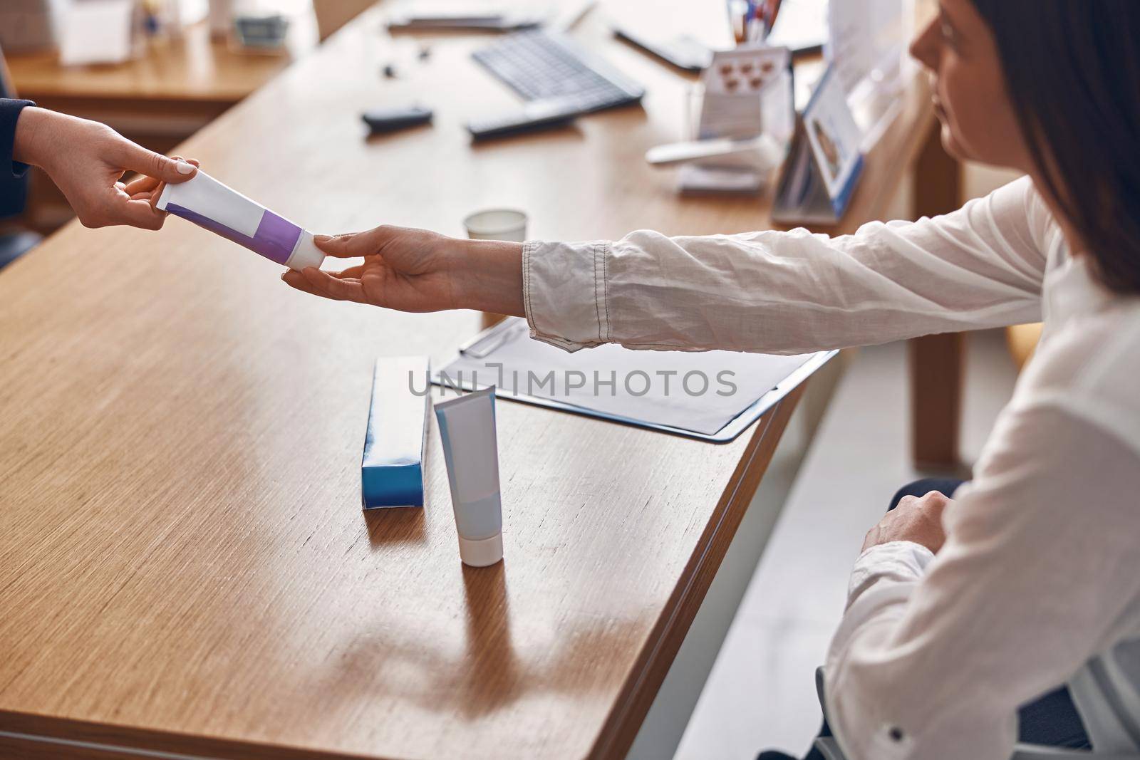 Happy woman is taking a toothpaste from hands of clinic personal