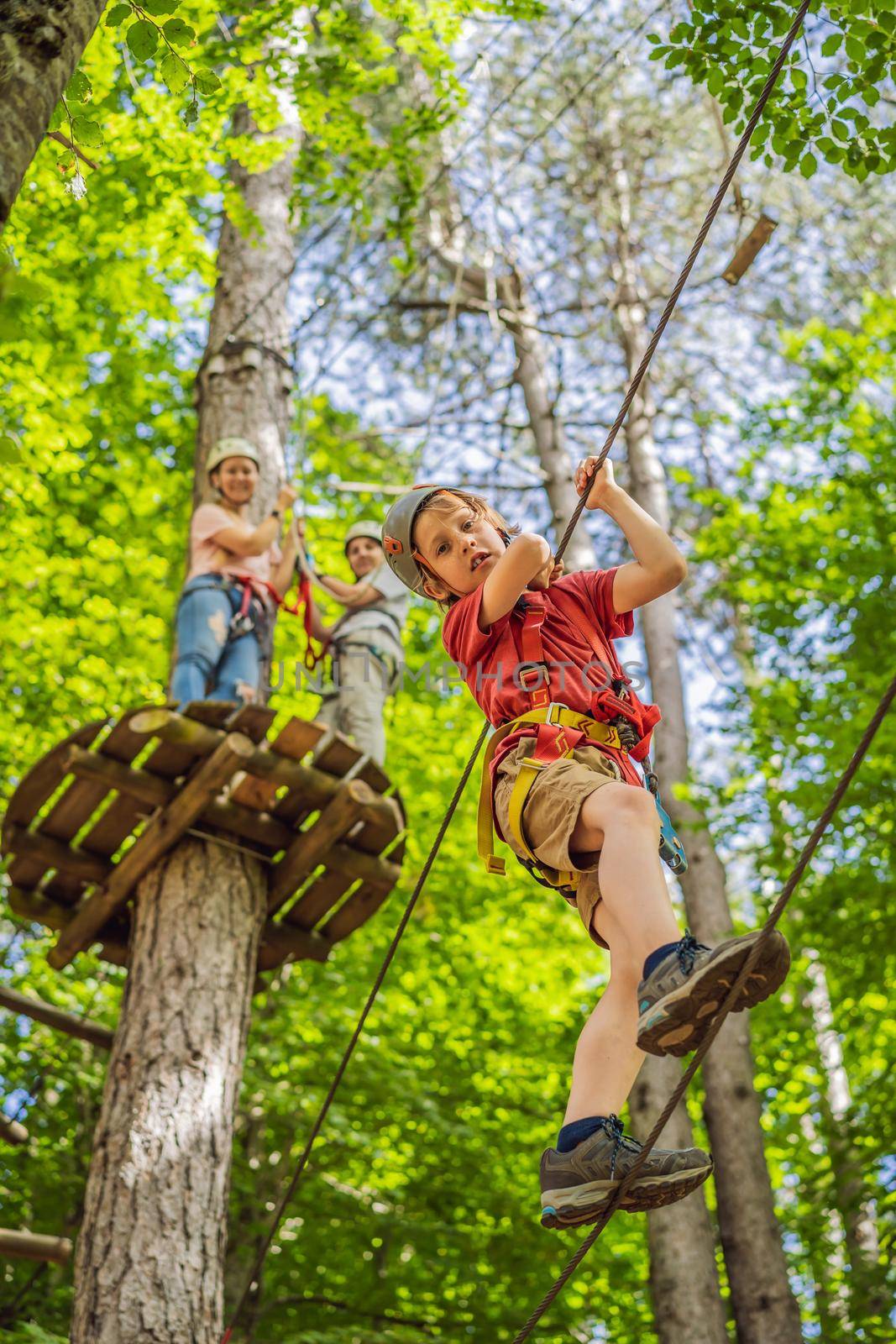 Friends on the ropes course. Young people in safety equipment are obstacles on the road rope by galitskaya