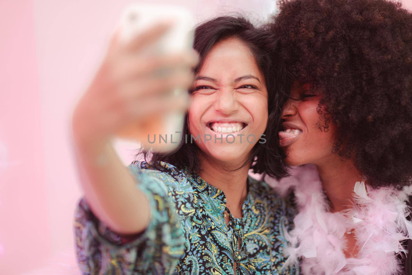 Couple of young south asian woman and african amercian woman having fun taking selfies in a bar.