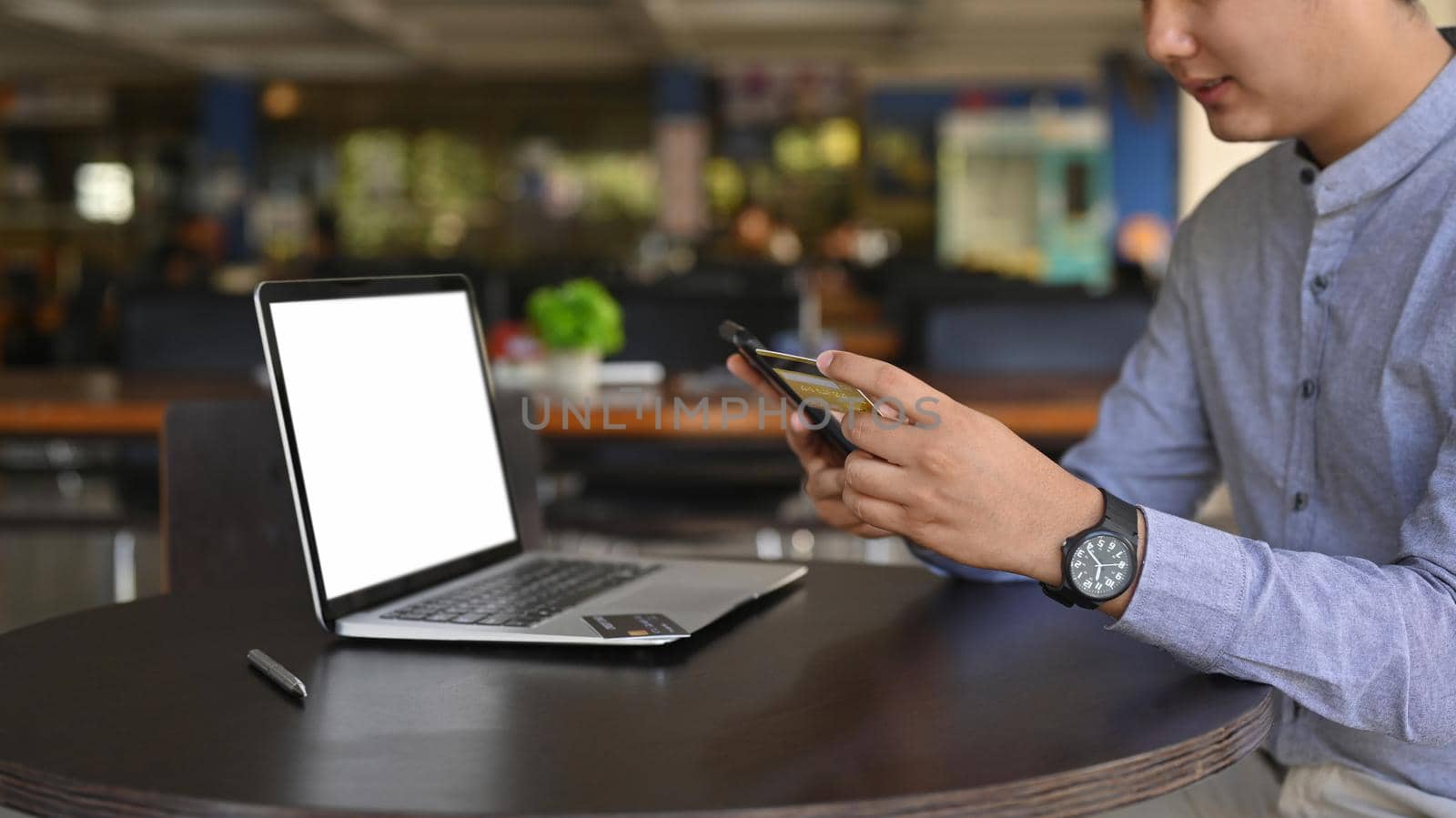 Asian business man sitting in front of laptop and using smart phone. by prathanchorruangsak