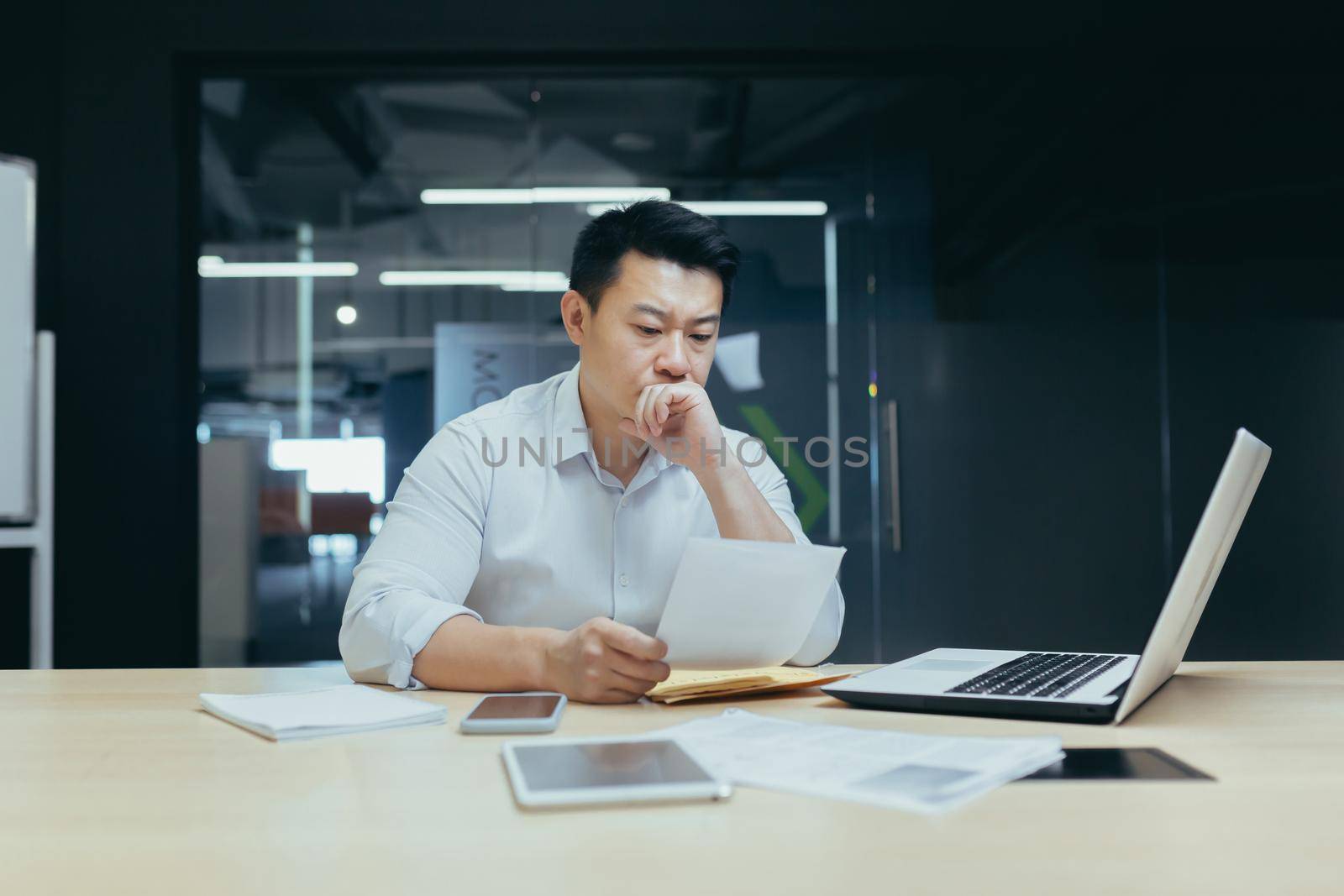Stressed young asian businessman working from office report annoyed with low sales. Nervous boss see c mistake incorrect information in paper document