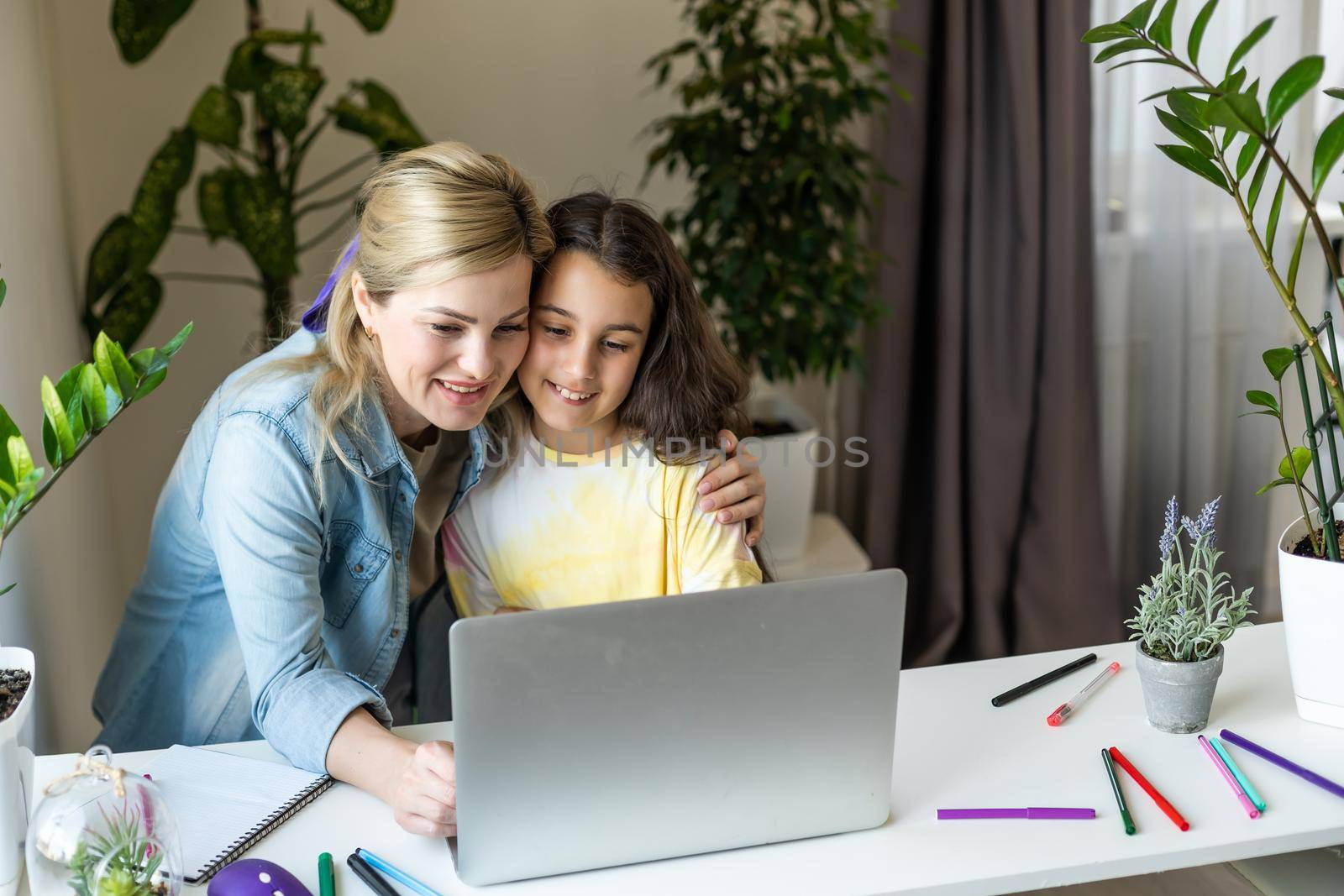 Friendship of mom and her cute little daughter. They wallow at home in casual clothes and shopping online together using a laptop. They buy new toys for pretty little girl.