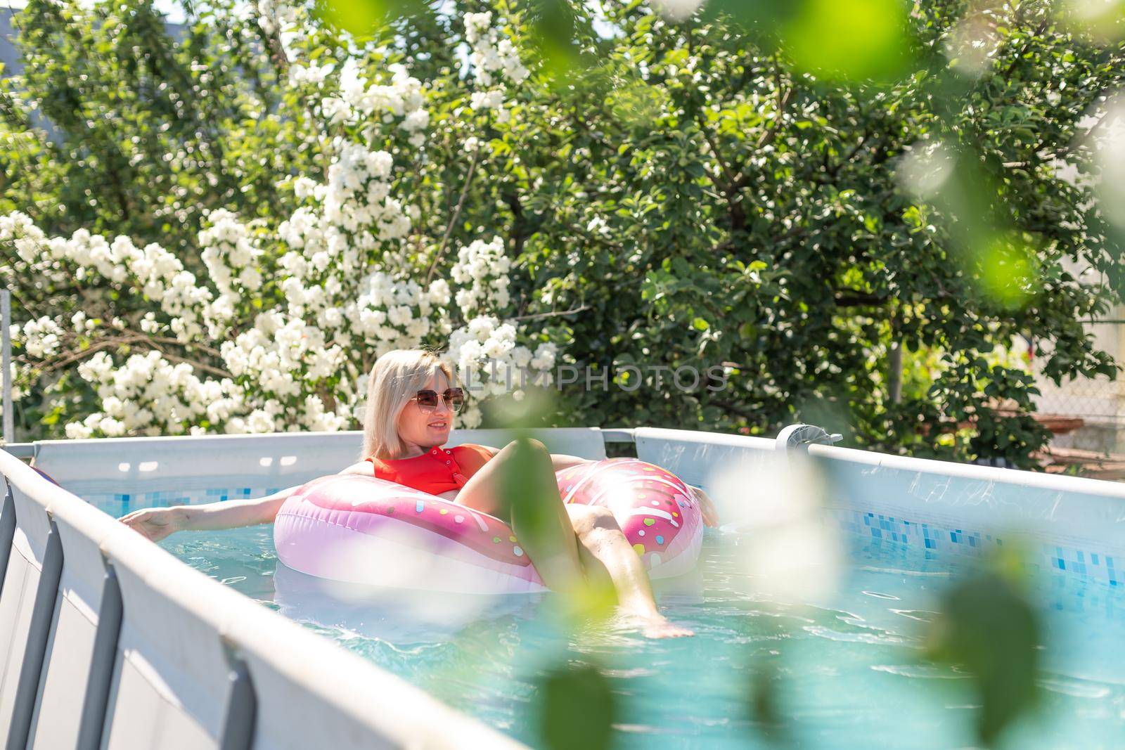 The young beautiful woman swims in the pool in a garden