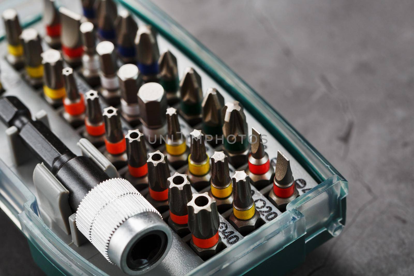 A set of metal power bits in a box on a gray background, for repair and maintenance