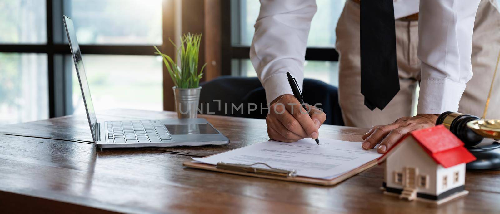 Close up young businessman standing near table with pen in hands, ready signing profitable offer agreement after checking contract terms of conditions, executive manager involved in legal paperwork.. by nateemee