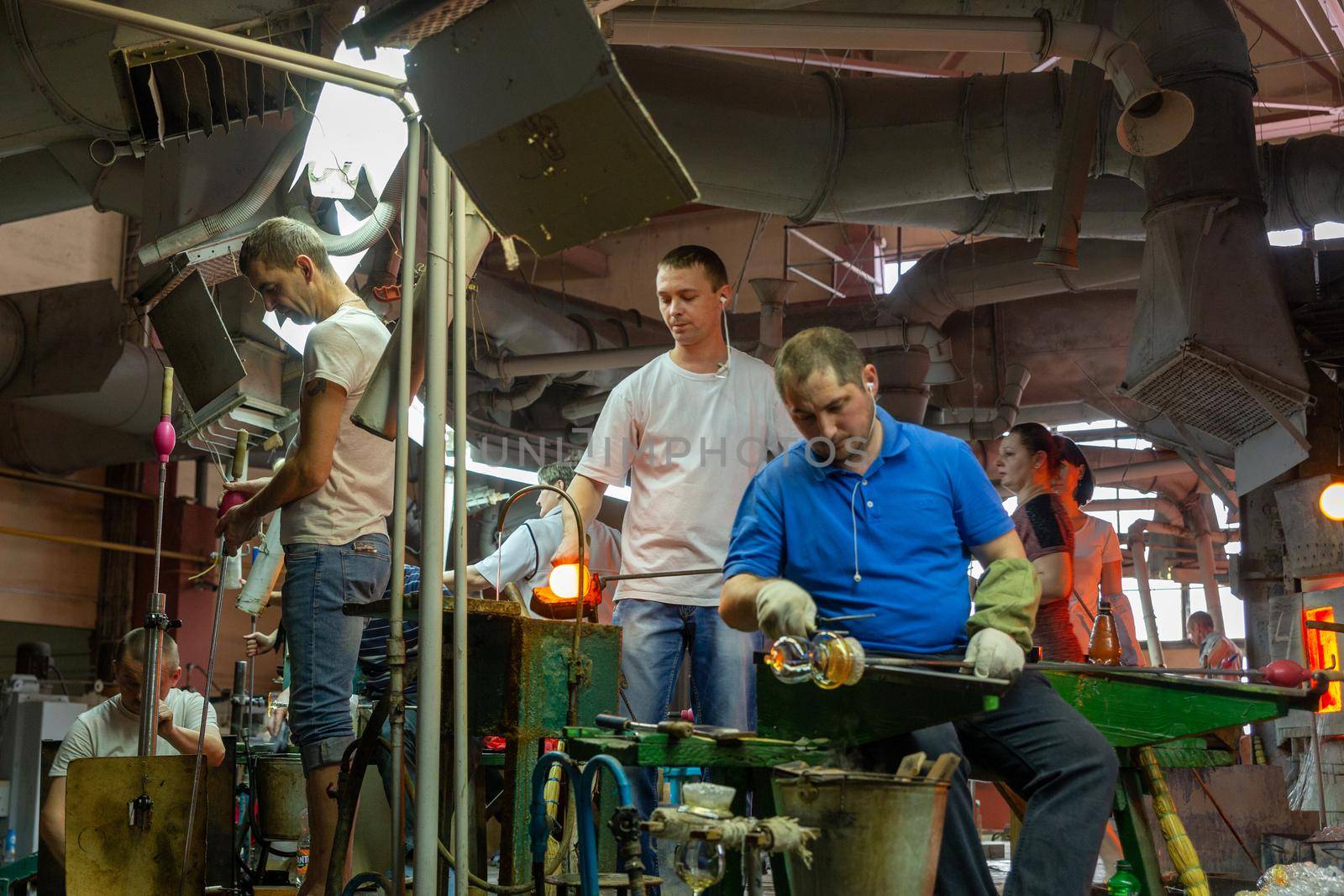 Beryozauka, Belarus - March 07, 2022: A team of glass blowers is working on the manufacture of glass vases and glasses. Up to 20 workers can be involved simultaneously in the production of particularly complex products.