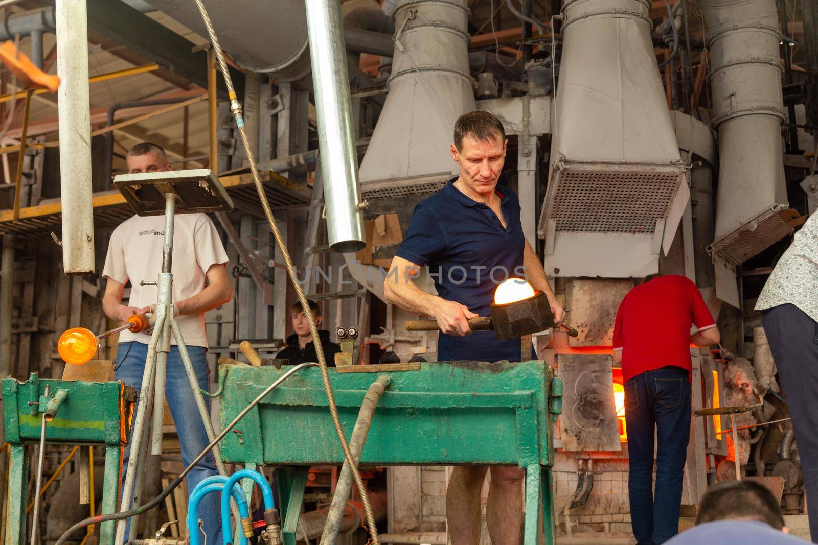Beryozauka, Belarus - March 07, 2022: A team of glass blowers is working on the manufacture of glass vases and glasses. Up to 20 workers can be involved simultaneously in the production of particularly complex products.