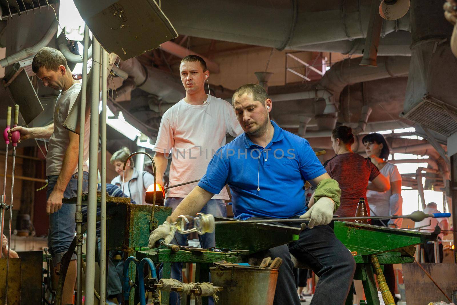 Beryozauka, Belarus - March 07, 2022: A team of glass blowers is working on the manufacture of glass vases and glasses. Up to 20 workers can be involved simultaneously in the production of particularly complex products.