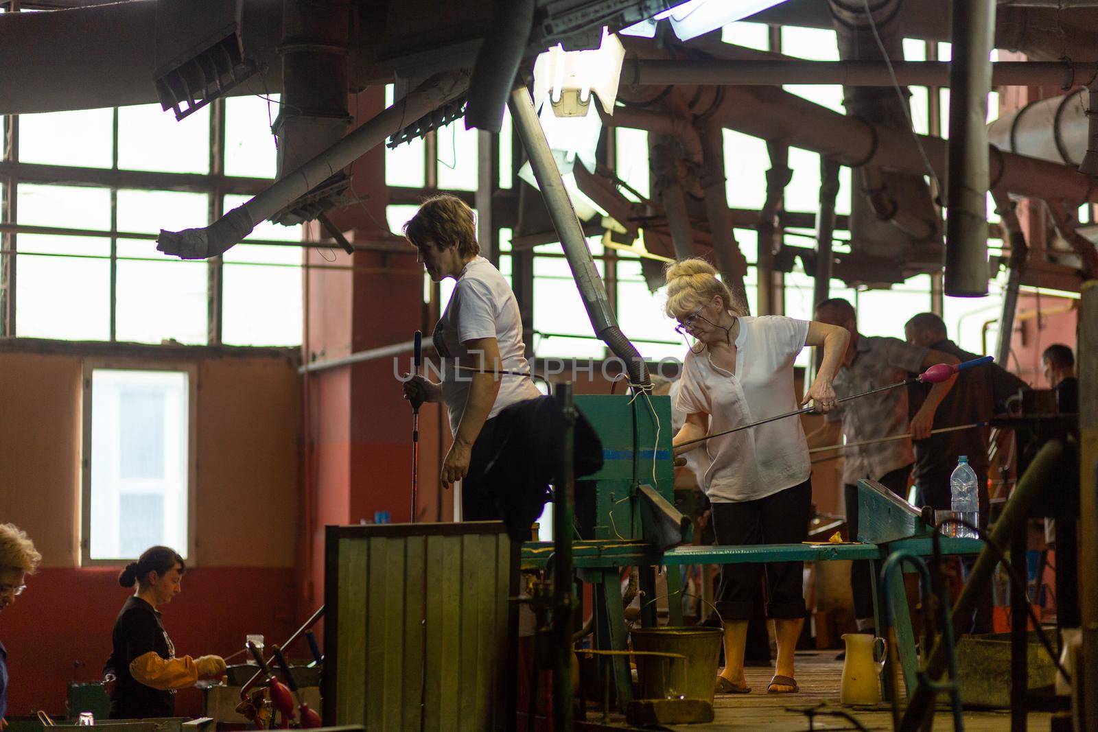 Beryozauka, Belarus - March 07, 2022: A team of glass blowers is working on the manufacture of glass vases and glasses. Up to 20 workers can be involved simultaneously in the production of particularly complex products.