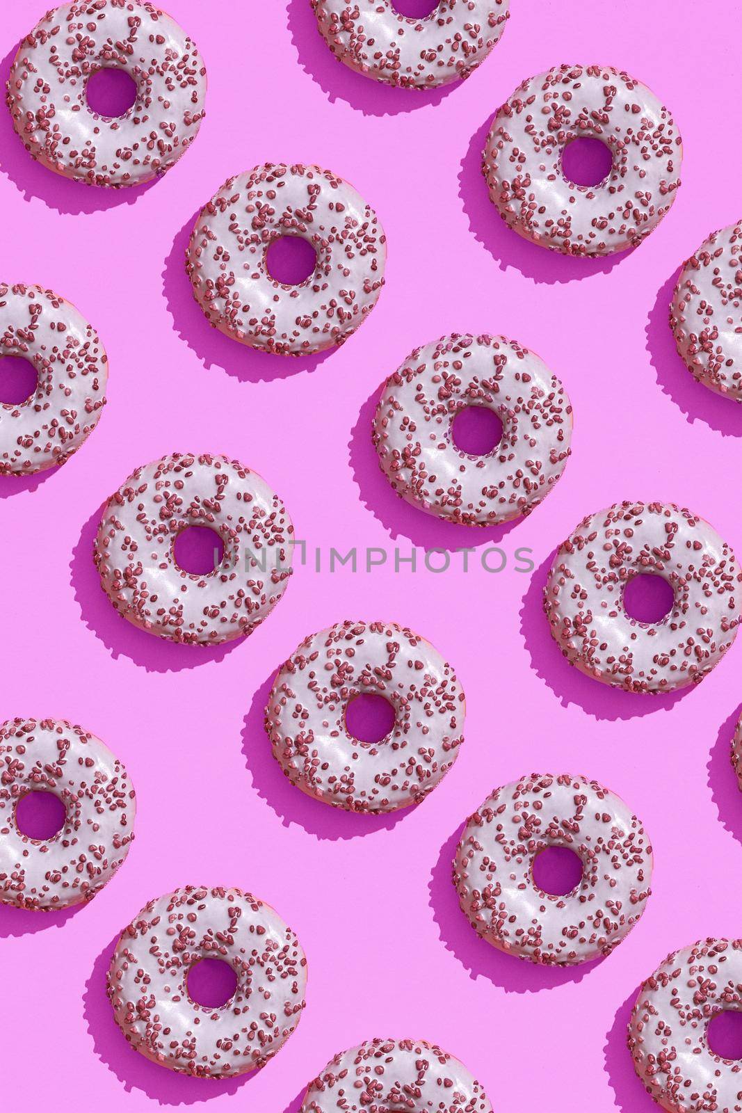 Food design with tasty pink glazed donut on purple lilac pastel background top view pattern by nazarovsergey