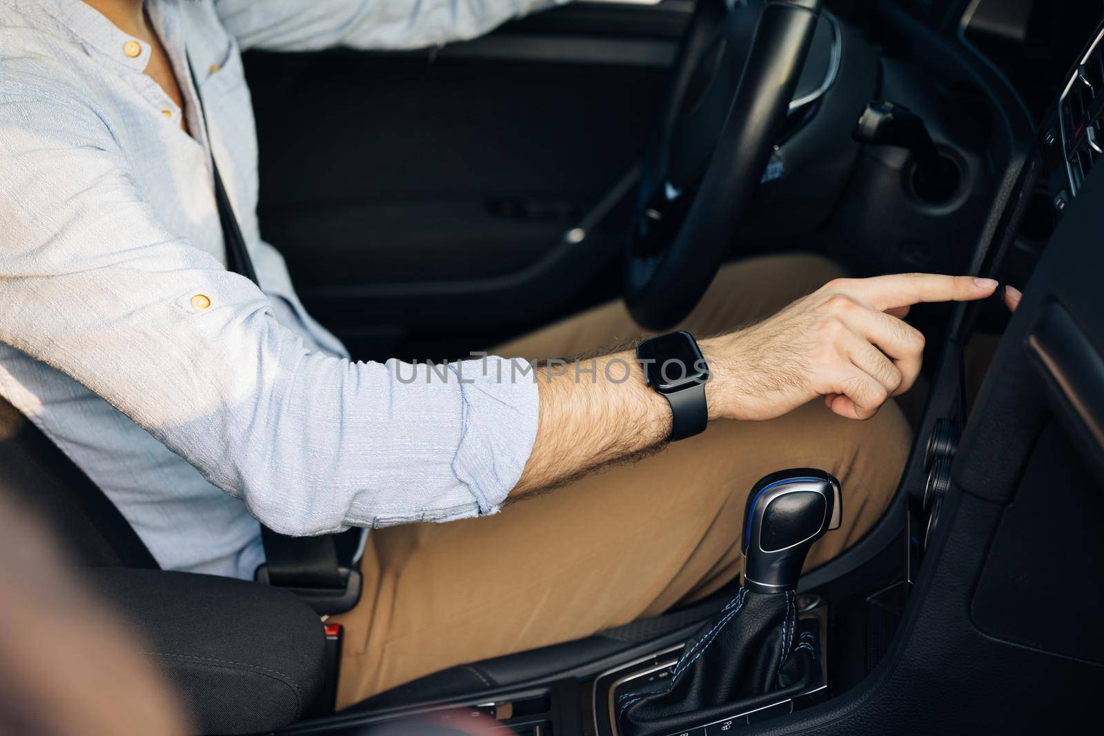 Unrecognizable man hand touching, clicking, tapping, sliding, dragging and swiping on screen monitor on modern luxury car. Interface concept.