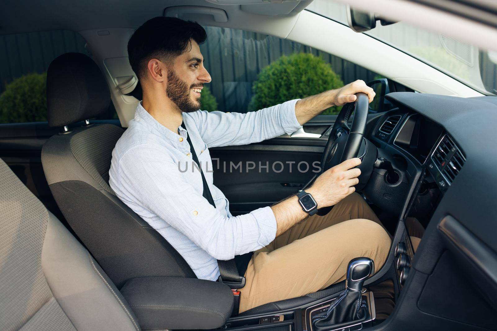 Handsome bearded man driving electric car commuting to work. Confident man driving sitting in the car at sunset. Look around. Automobile businessman traffic transportation work city by uflypro