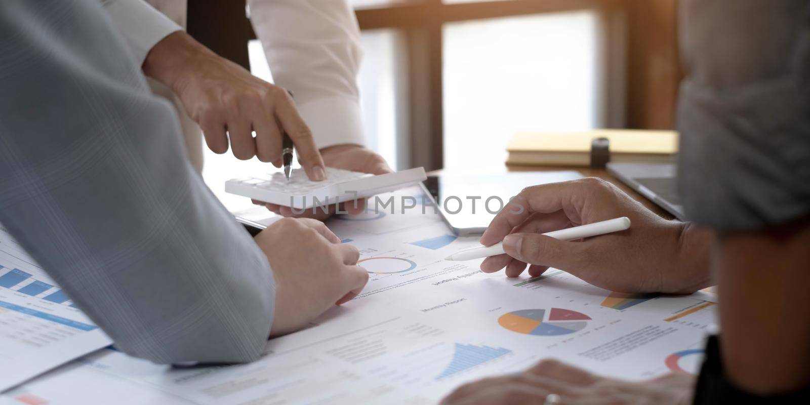 Business People Meeting using laptop computer,calculator,notebook,stock market chart paper for analysis Plans to improve quality next month. Conference Discussion Corporate Concept by wichayada