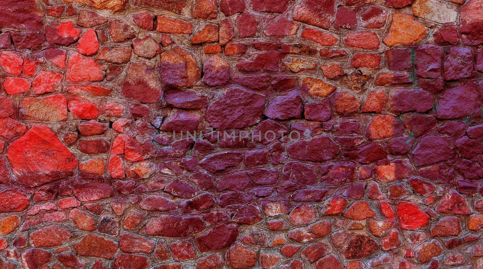 a stone wall with stones of different shades of red. by gelog67