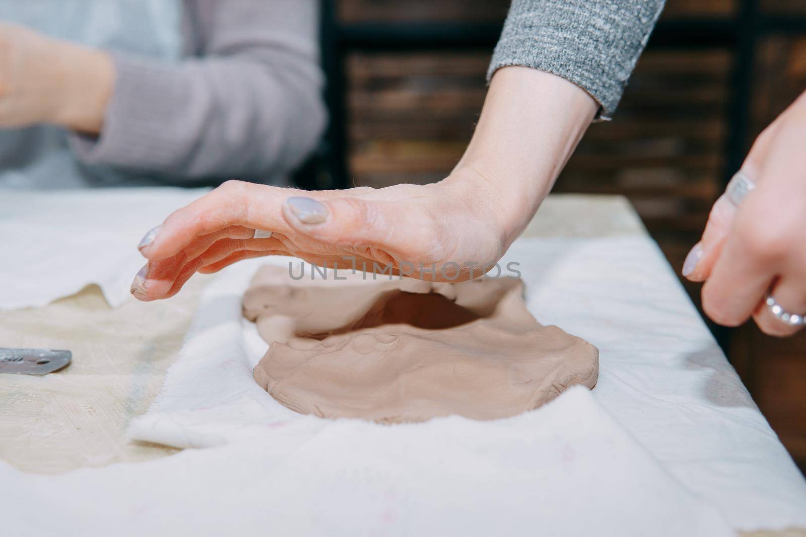 Female hands kneading clay. Production of ceramic products at the master class on ceramics. Close-up.