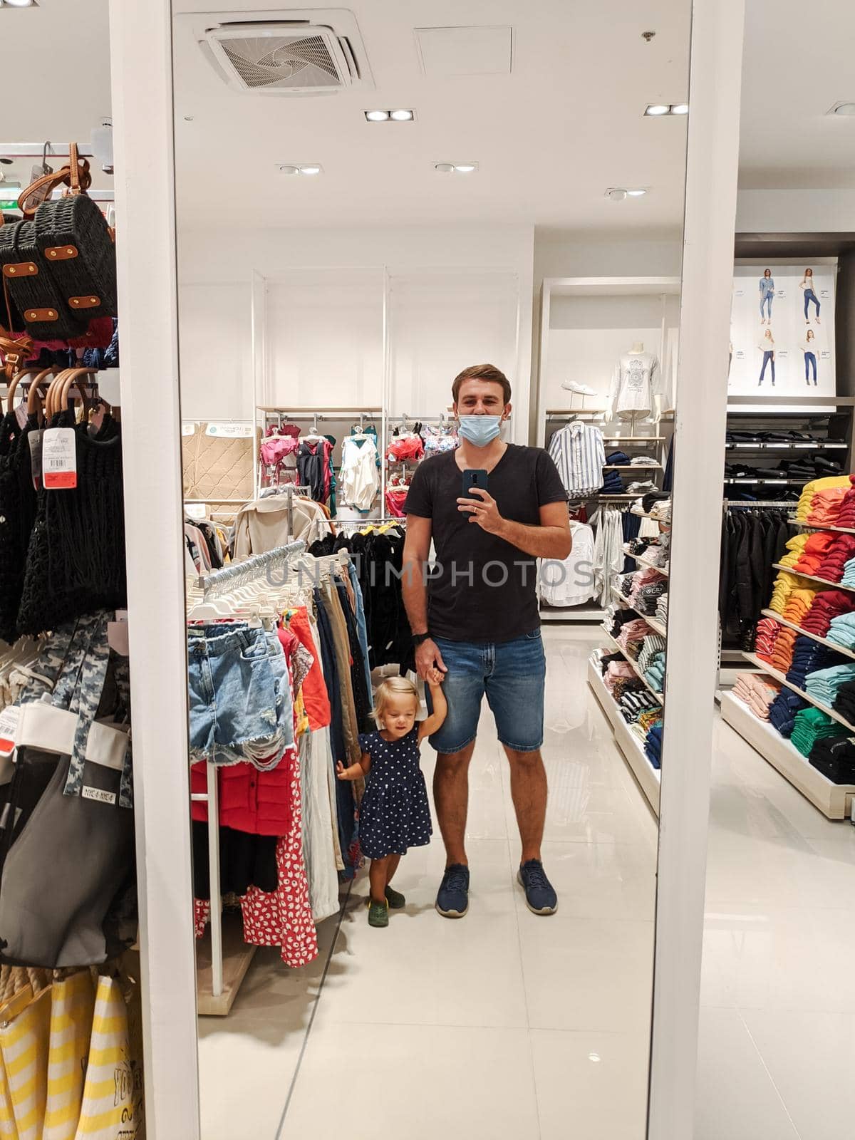 Dad with a little girl is photographed in a mirror in a clothing store. High quality photo