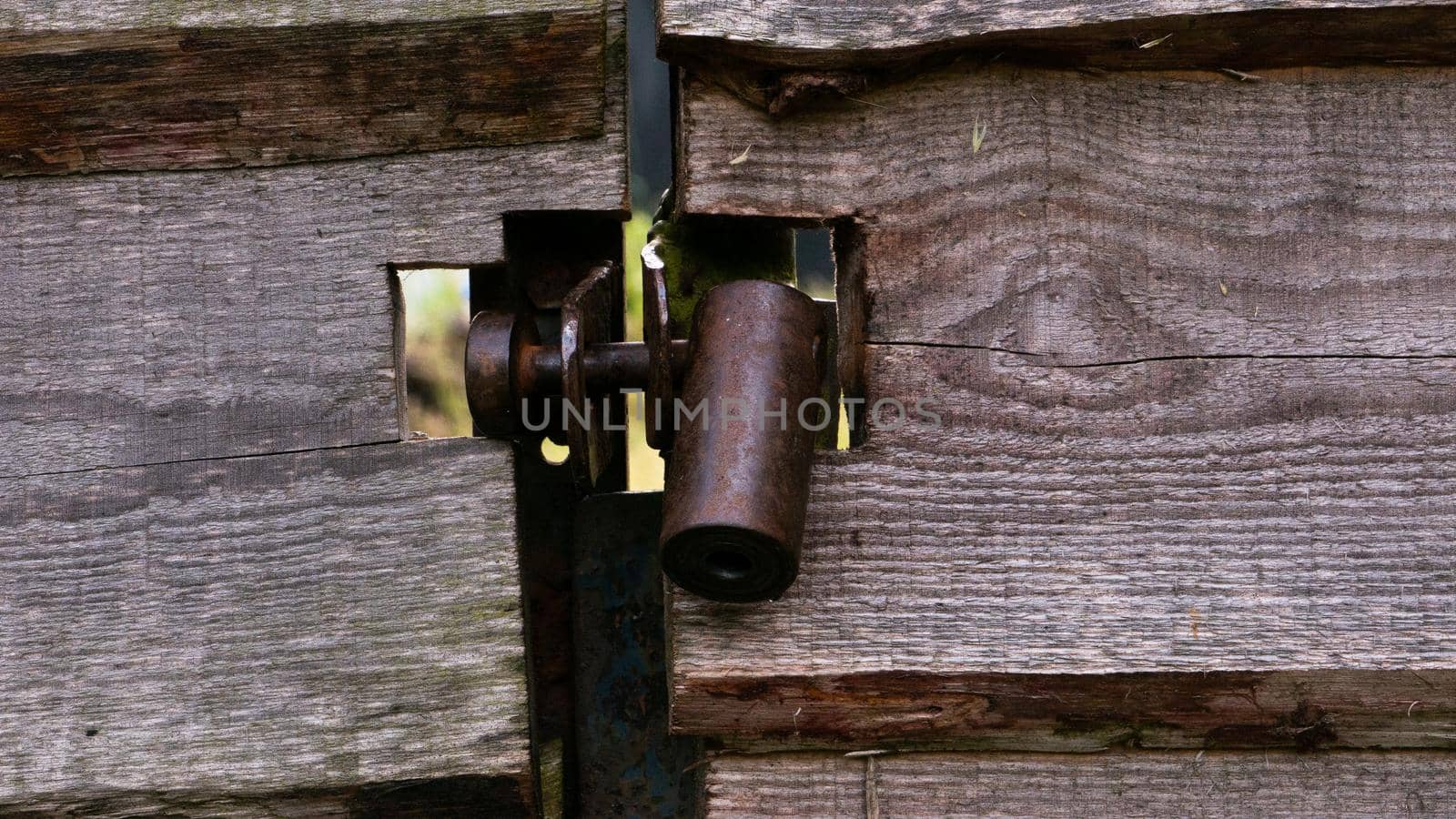 Hanging metal lock on a wooden gate. A dark metal castle in close-up in a gate made of wooden planks.