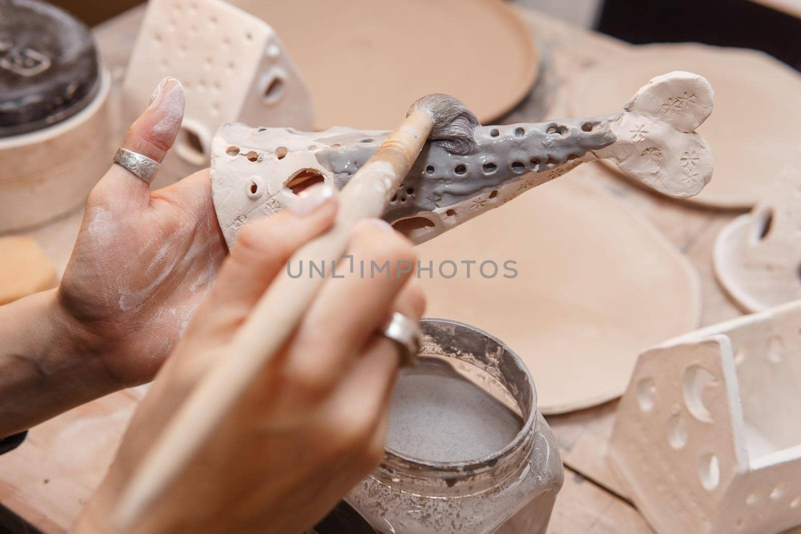 A master ceramist holds a clay product in his hands. Making a ceramic candle holder from clay. The process of coating the candlestick with glaze. Close-up.