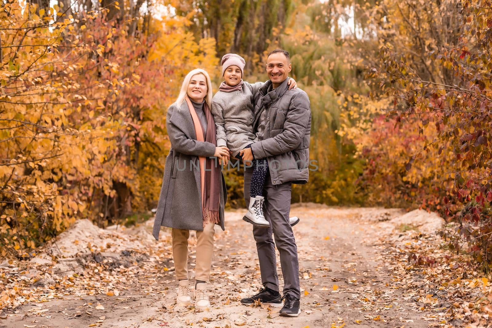 A Family of four enjoying golden leaves in autumn park by Andelov13