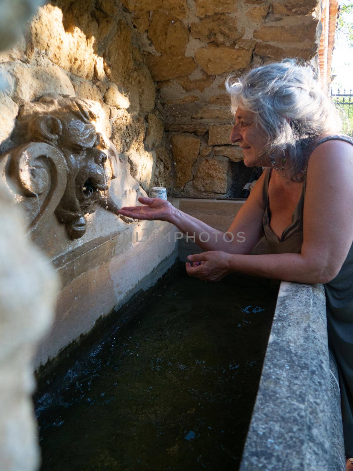Woman watering and washing on a public foutain in Castell'Arquato Italy.Pure and precious to nature. Shot of hands held out to catch a stream of water outside.
